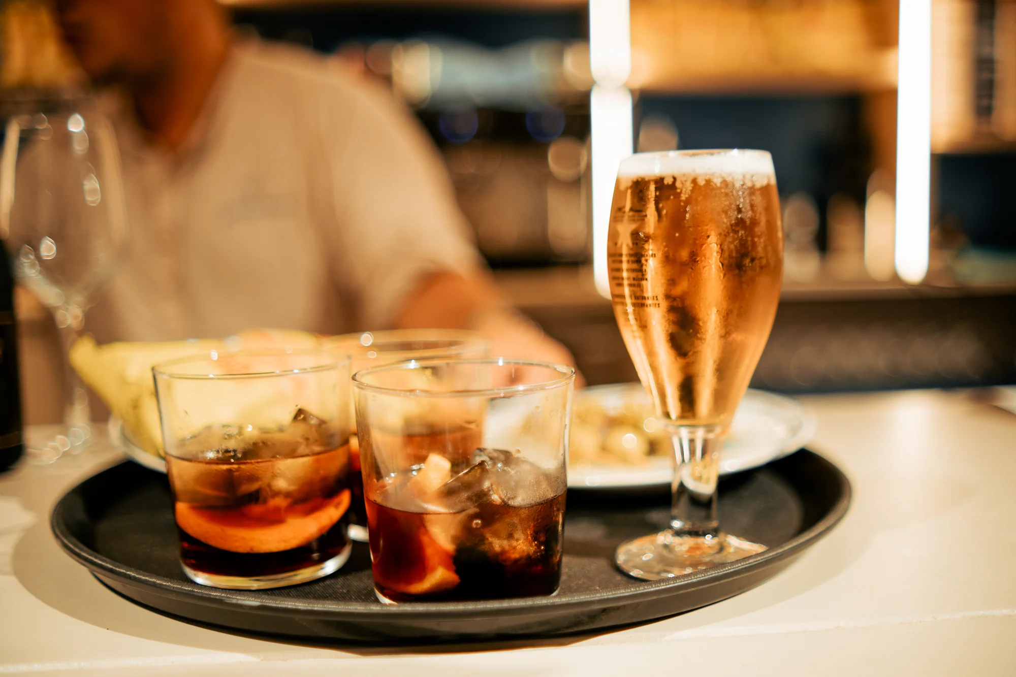 Bandeja de aperitivo con conservas abiertas, pan y vasos de vermut servidos sobre la mesa